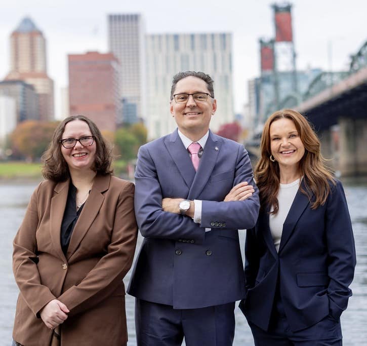 Romano Law P.C. Portland divorce and family law attorneys Marissa Martinez, Michael G. Romano, and Brandi Becker on the bank of the Willamette River with the Portland skyline in the background.